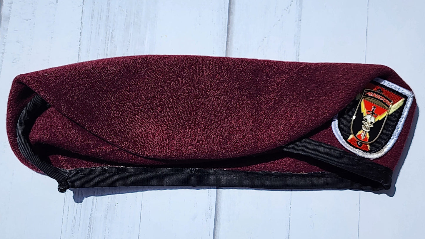 Maroon pouch with a black strap on a light wooden surface