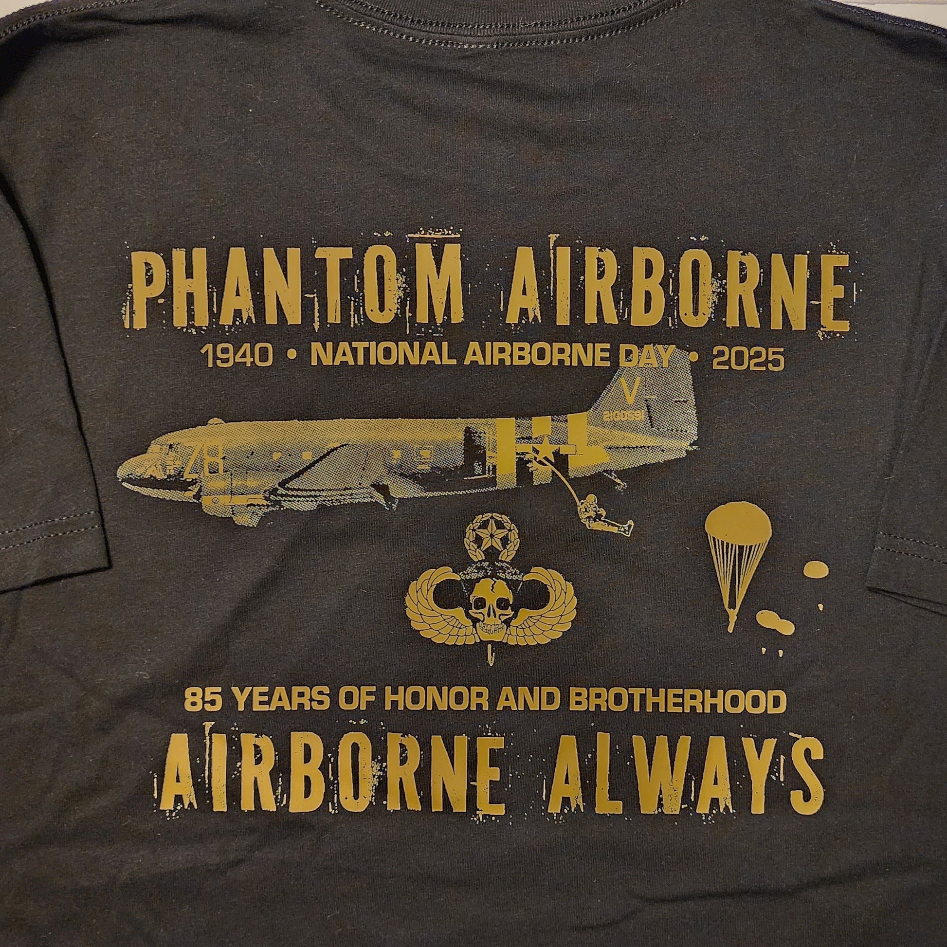 Black t-shirt with gold text and graphics on a wooden surface