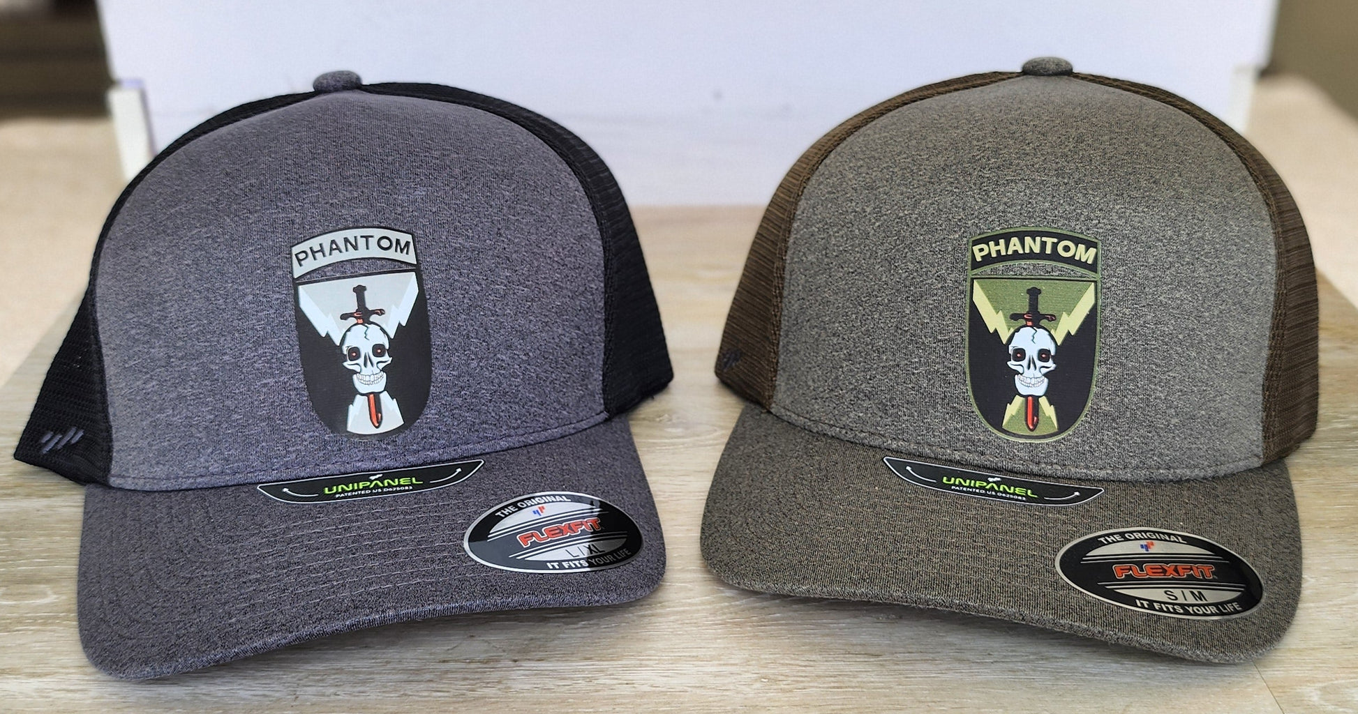 Two gray and black caps with logos on a wooden surface