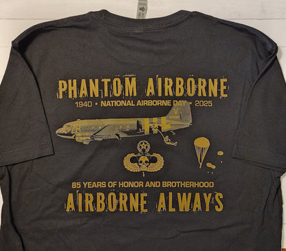 Black t-shirt with gold graphics and text on a wooden surface