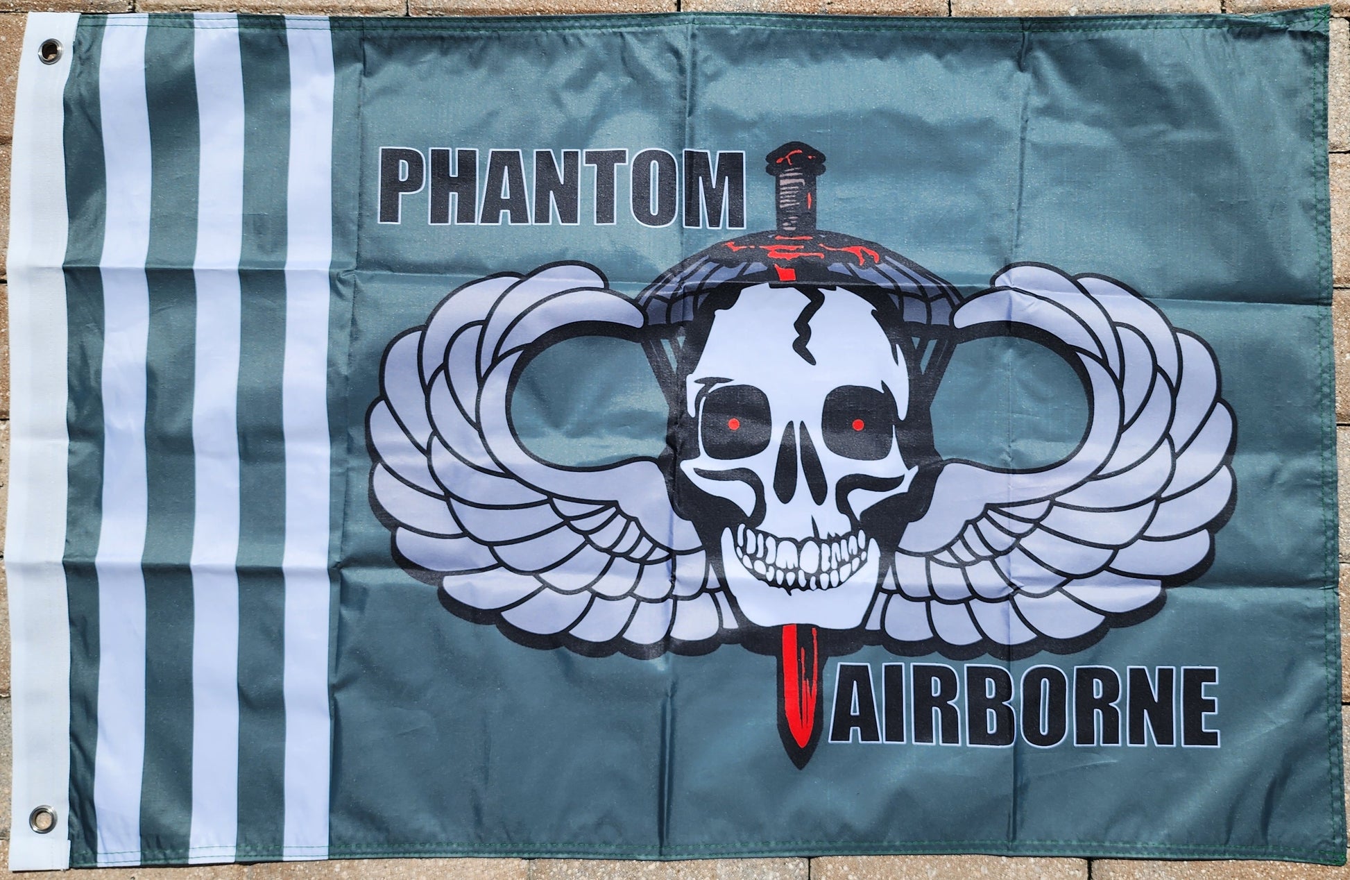 Flag with a skull design and 'Phantom Airborne' text on a brick wall background