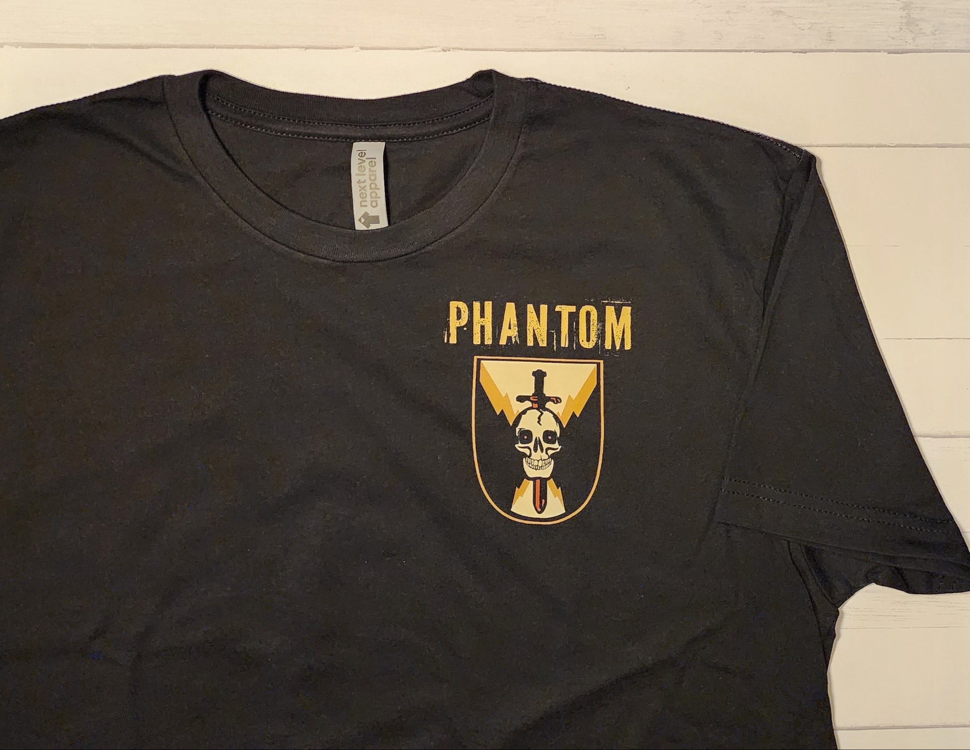 Black t-shirt with 'Phantom' logo on a wooden background